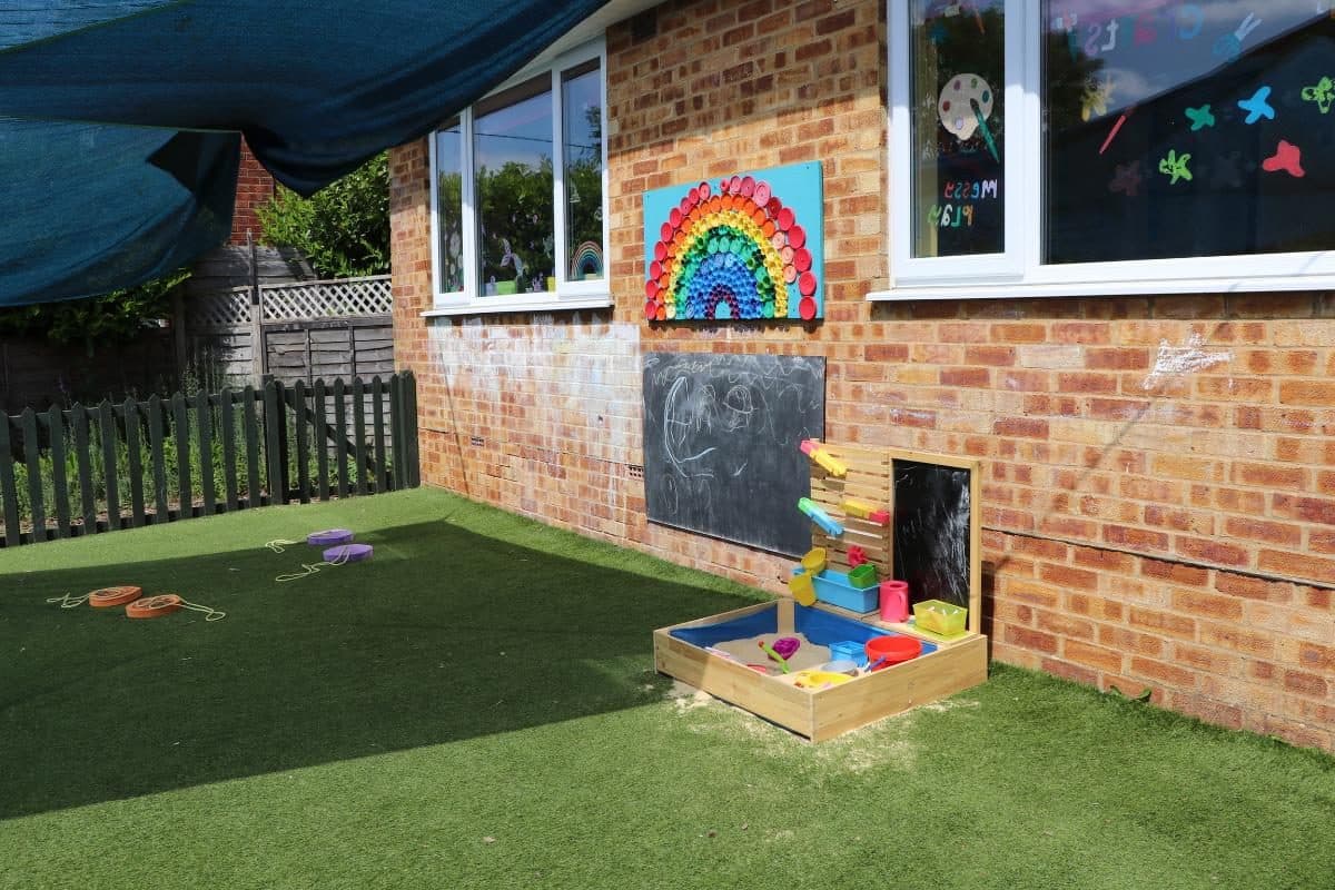 Outdoor learning space with chalkboard and rainbow display at Hazlemere nursery